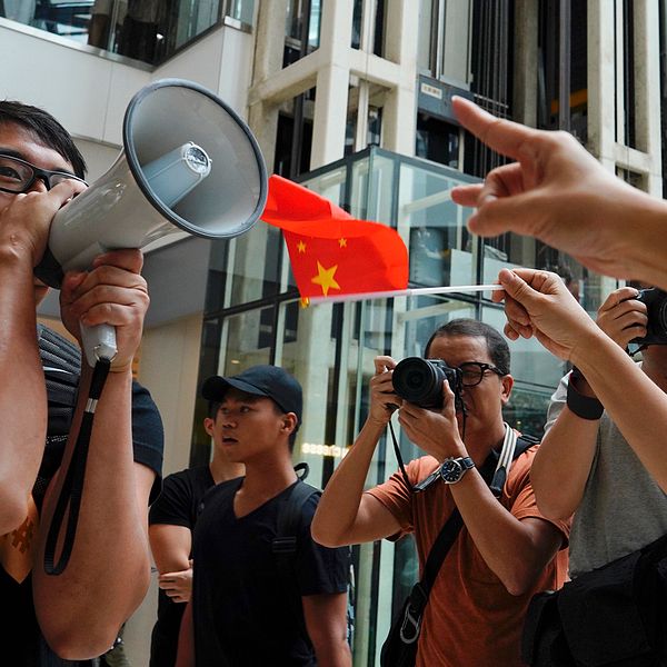 En demonstrant från proteströrelsen försöker göra sin röst hörd framför prokinesiska demonstranter i ett köpcentrum i Hongkong. Bild tagen fredag 13 september.