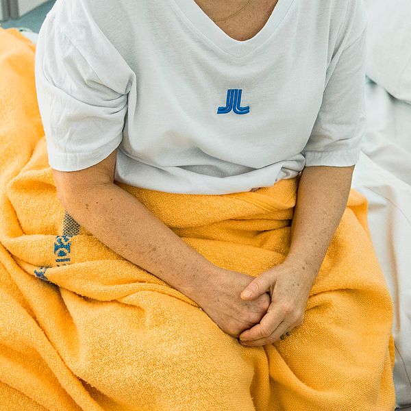 Kvinna som sitter i sjuksäng.