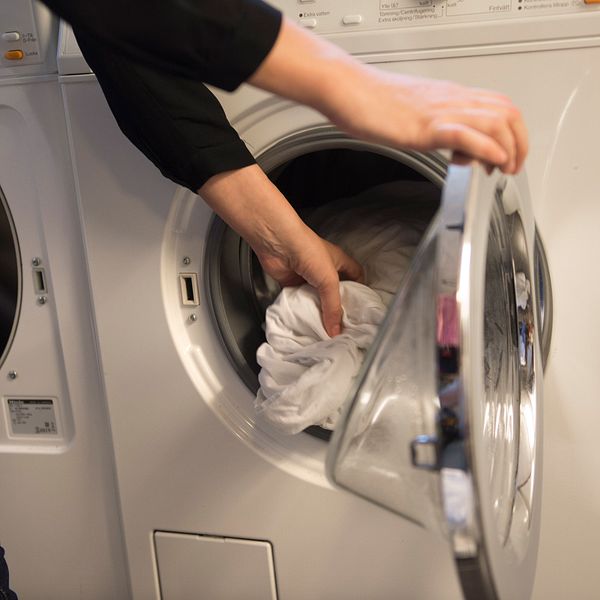 Kvinna tar ut tvätt ut en tvättmaskin.
