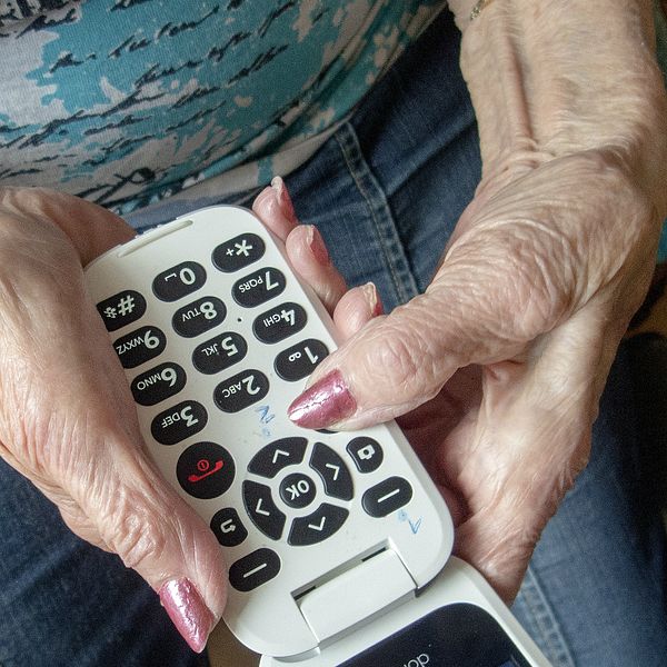 Kvinna håller i en knapptelefon.