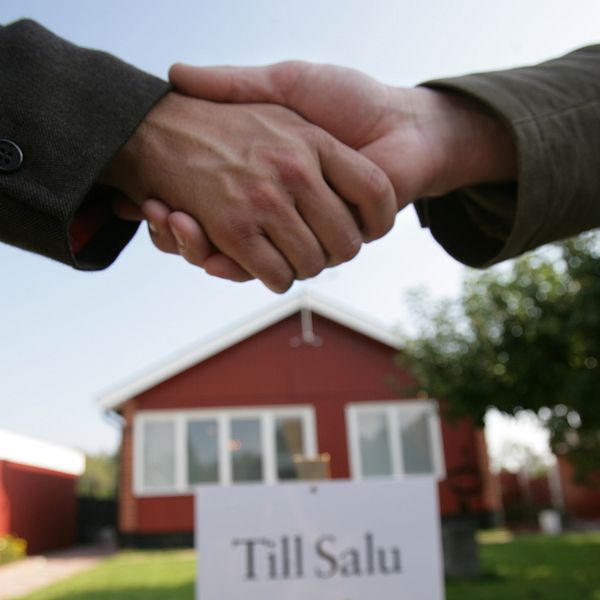 Två personer som skakar hand framför ett hus som sålts.