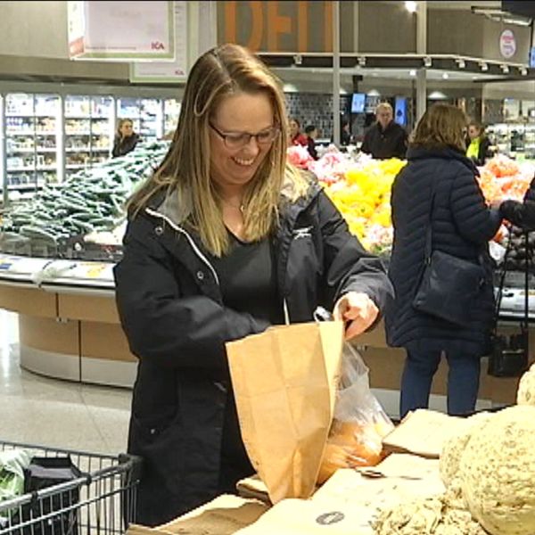 Camilla Gartz står i en butik och plockar i frukt i en matavfallspåse