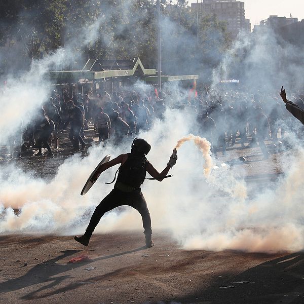 En demonstrant i Chile kastar tårgas.