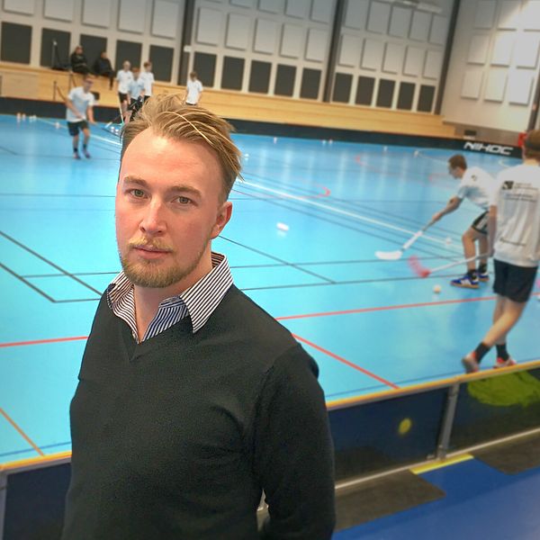 Porträttfoto på Jakob Westerlund, distriktschef på Gästriklands och Hälsinglands innebandyförbund. I bakgrunden spelar ungdomar innebandy.