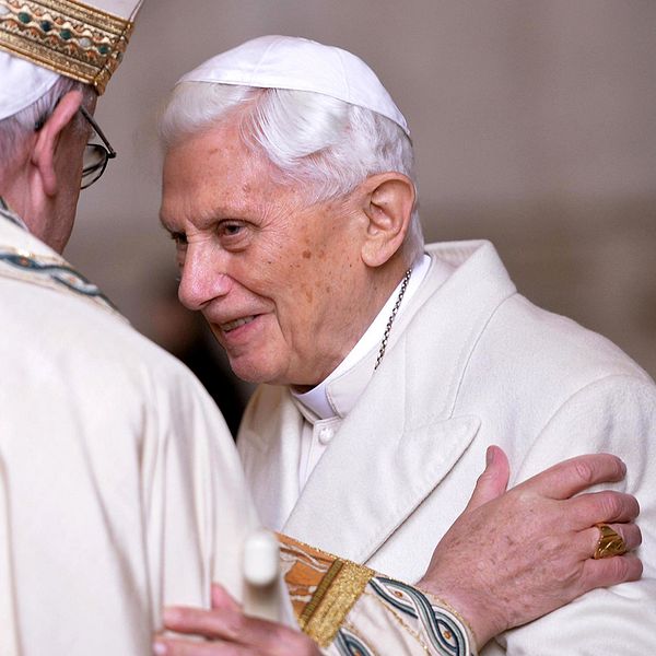 Till vänster ryggen av påven Franciskus som talar med påven emeritus Benedictus XVI. Arkivbild.