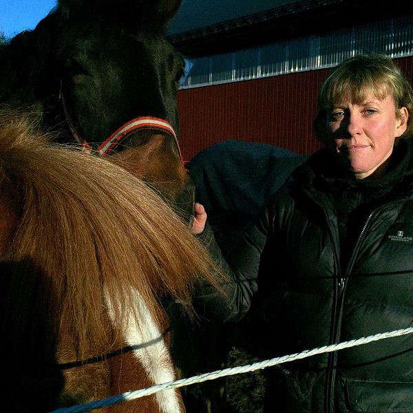 Kvinna står intill två hästar