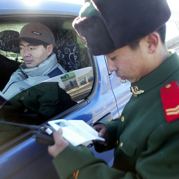 En kinesisk gränspolis kollar passen för två personer i en bil vid gränsen mellan Kina och Ryssland