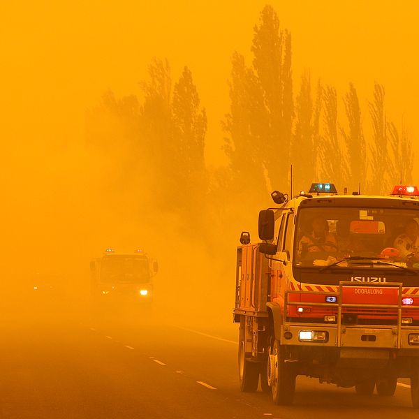 En brandbil kör genom rödgul rök i Australien