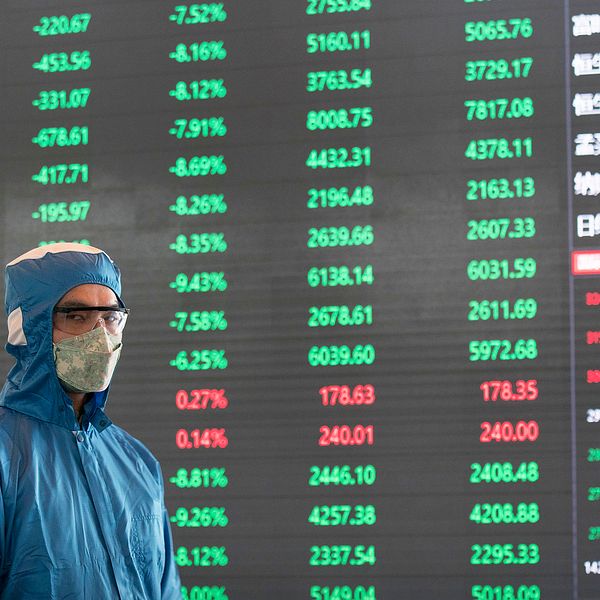 En arbetare framför en börsskärm i Shanghai där kompositindex rasade med drygt 8,7 procent vid öppning.