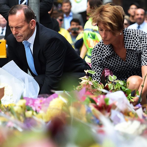 Premiärminister Tony Abbott (L) och hans fru Margaret lägger ner blommor nära den plats där det blodiga gisslandramat fick sitt slut.
