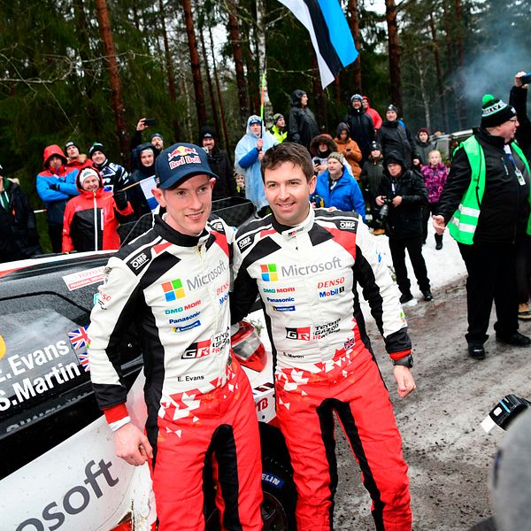 Elfyn Evans och Scott Martin poserar för bilder samtidigt som publik syns i bakgrunden.