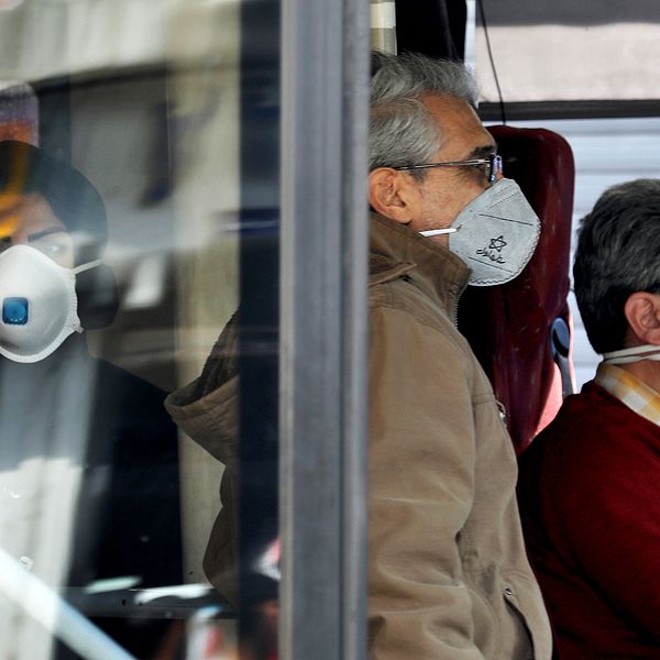 Människor med ansiktsmask åker buss i Teheran.