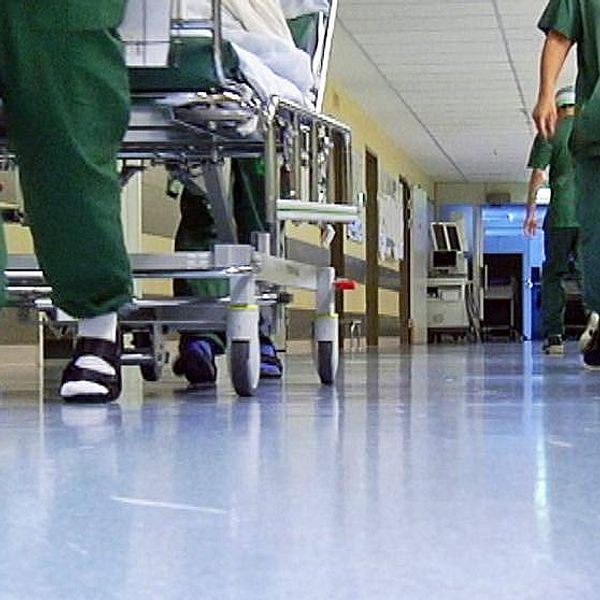 vårdpersonal i sjukhuskorridor, man ser deras ben och fötter