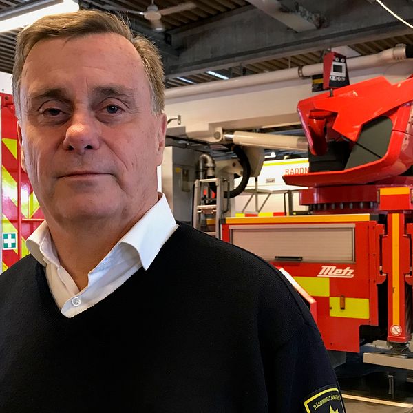 Jan står i brandstationen i Varberg, i bakgrunden syns rödgula brandfordon, brandbilar mm