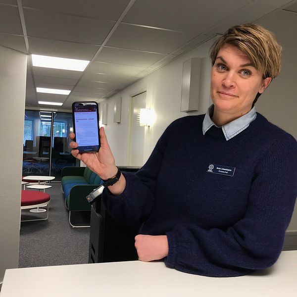 Anna Löwenhamn håller upp en mobiltelefon.