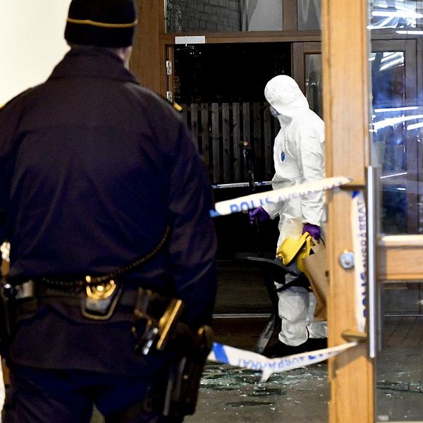 En polis och en tekniker i en entré som skadats av en explosion