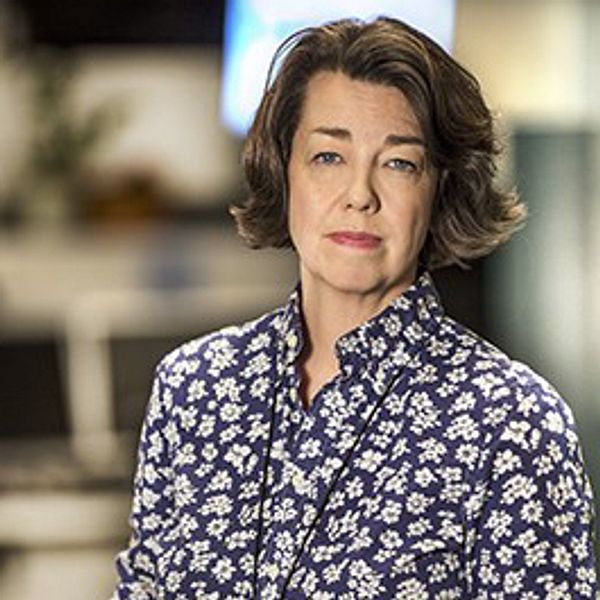 Porträttfoto på Pia Bernhardson, utrikeschef på SVT. Hon har blåvitblommig skjorta på sig.