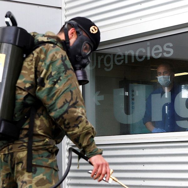 En spansk militär desinficerar utanför ett sjukhus i Barcelona.
