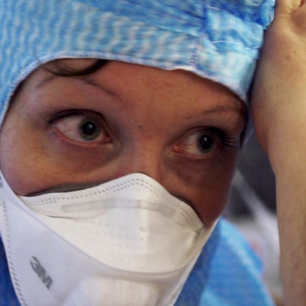 Munskydd, vårdpersonal får hjälp att ta på sig munskydd, sjukhus
