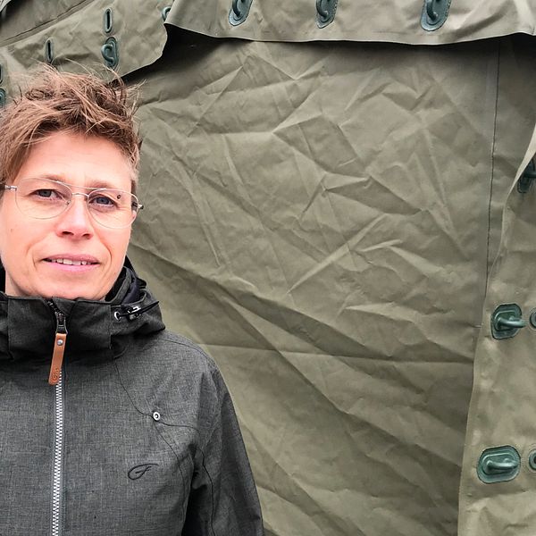Kvinna står framför ett grönt corona-tält.