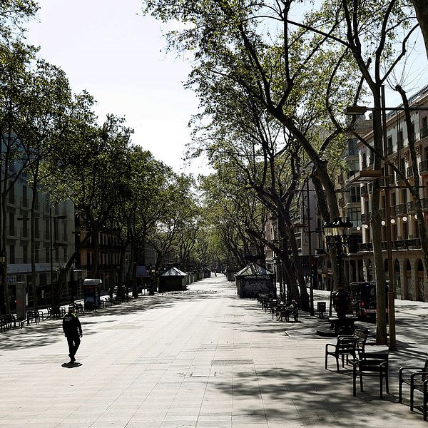 En ensam person syns promenera ned för en folktom gata i Barcelona.