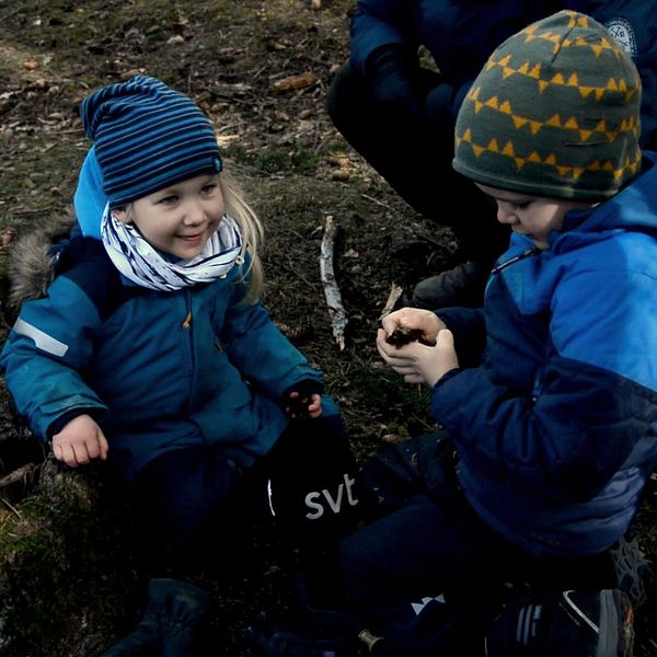 Två barn som leker i skogen.