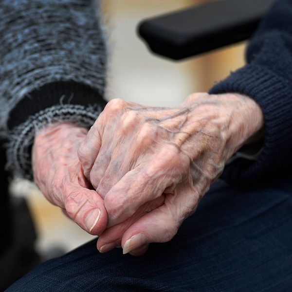Äldre personer håller varandra i handen.