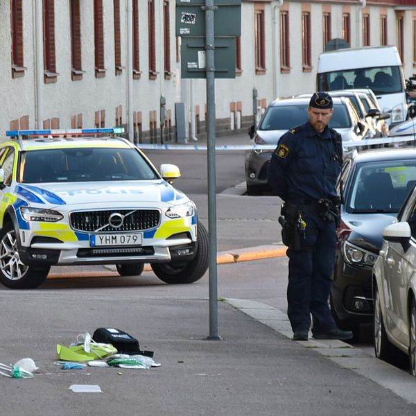 polisbilar och bilar vid trottoar, polisman står och tittar på saker som ligger på marken