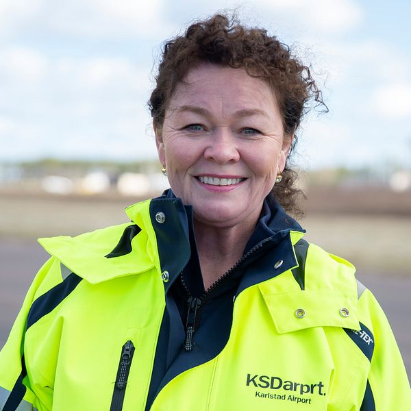 Camilla Sperling i en ljusgul jacka med Karlstad airports logotyp.