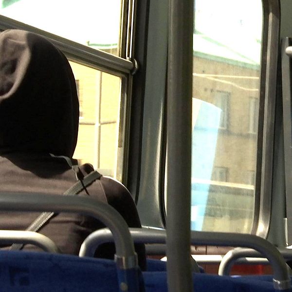 Kvinna på buss med luva.