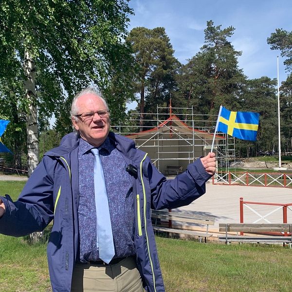 Peter Friström, ordförande i kommunfullmäktige (S) står framför scenen på Torekällberget och viftar med Sverige-flaggor