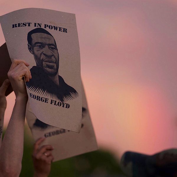 En demonstrant i Minneapolis håller upp en skylt med bild på George Floyd.