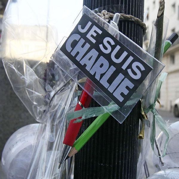 Blommor och pennor upphängda utanför Charlie Hebdos redaktion efter attentatet.