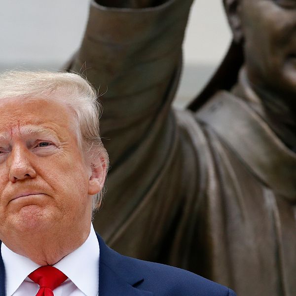 Donald Trump när han poserade framför statyn över påven Johannes Paulus II i tisdags.