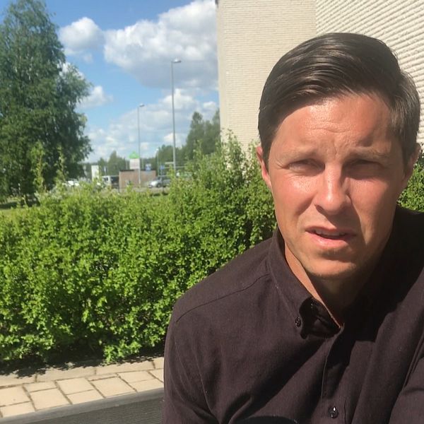 Regionschef för Företagarna i Västerbotten Jonas Nordin i svart skjorta intervjuad utomhus med buskar och husvägg i bakgrunden.