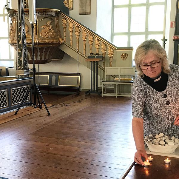 Kyrkoherden Lena Funge tänder ett ljus i Forsa kyrka.