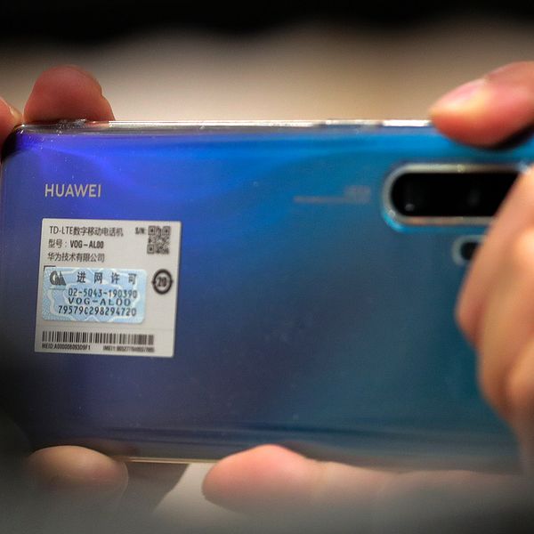 En person håller upp en blå Huawei-mobil.