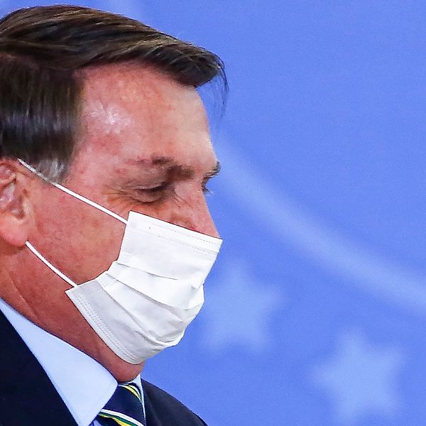 Närbild på Brasiliens president Bolsonaro i profil, iförd ansiktsmask under en formell tillställning.