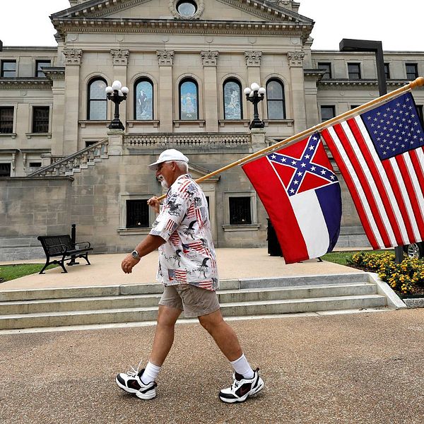 En man med den amerikanska flaggan och Mississippis nuvarande flagga med sydstatssymbolen.