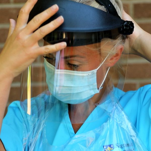 En sjuksköterska sätter på sig sin skyddsutrustning.