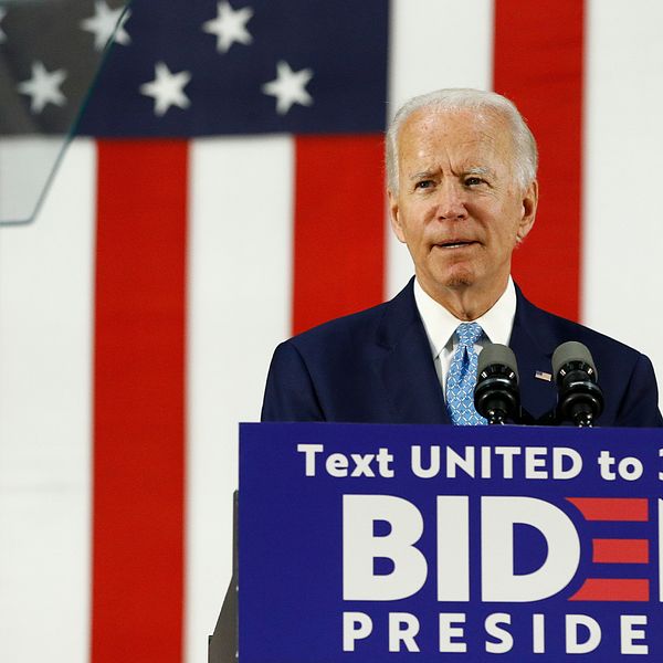 Amerikanske presidentkandidaten Joe Biden håller tal bakom podie med text där man uppmanas smsa ett nummer för att rösta fram Biden som president. Han står framför en stor amerikansk flagga.