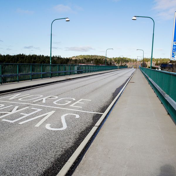 En asfalterad väg med orden Sverige och Norge skrivet i vit färg. Vid sidan om en blå skylt med texten ”Norge” i vitt.