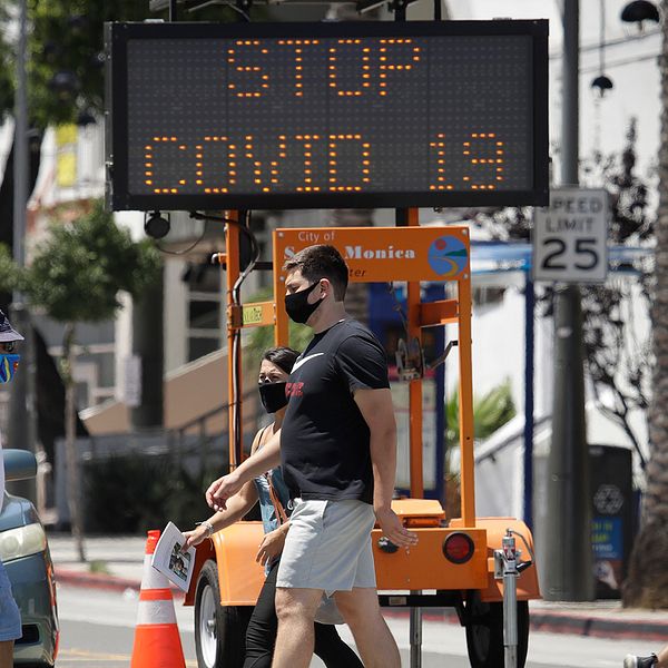 Santa Monica, Kalifornien. Fotgängare med munskydd korsar ett övergångsställe.