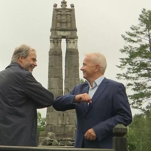 Georg Andrén och Knut Storberget gör en coronahälsning med armbågarna framför fredsmonumentet i Morokulien.