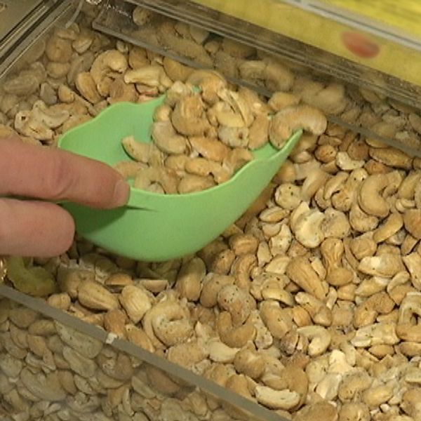 nräbild en hand som tar cashew-nötter ur lösviktslåda med en skopa