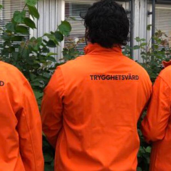 Tre trygghetsvärdar i orange jacka med texten – trygghetsvärd.