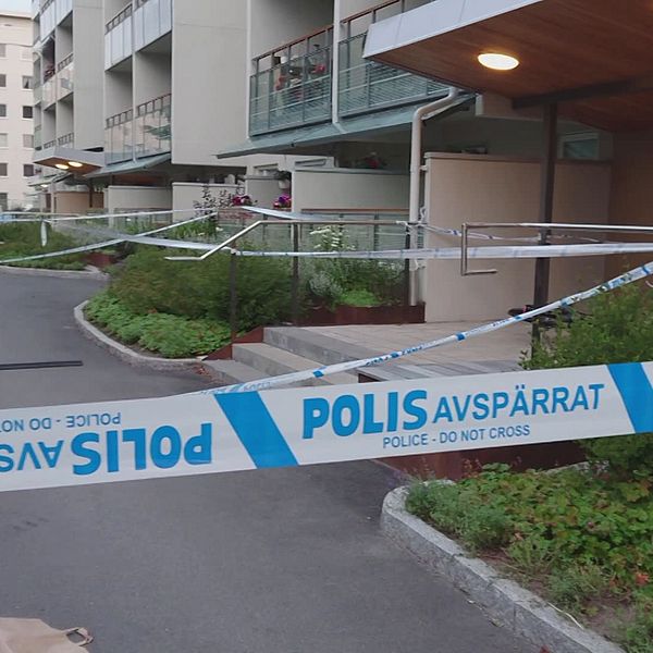 Bostadsområde i bakgrunden med av polisen uppsatt avspärrningstejp i förgrunden.