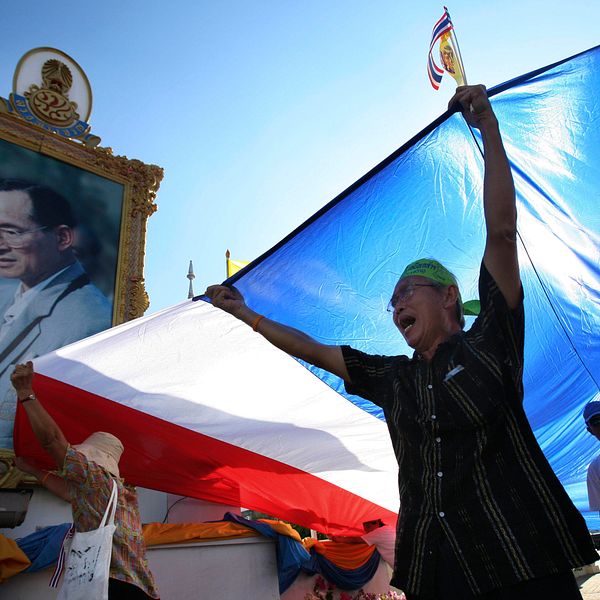 En supporter till regimen viftar med en flagga framför ett porträtt av den thailändska kungen Bhumibol Adulyadej.
