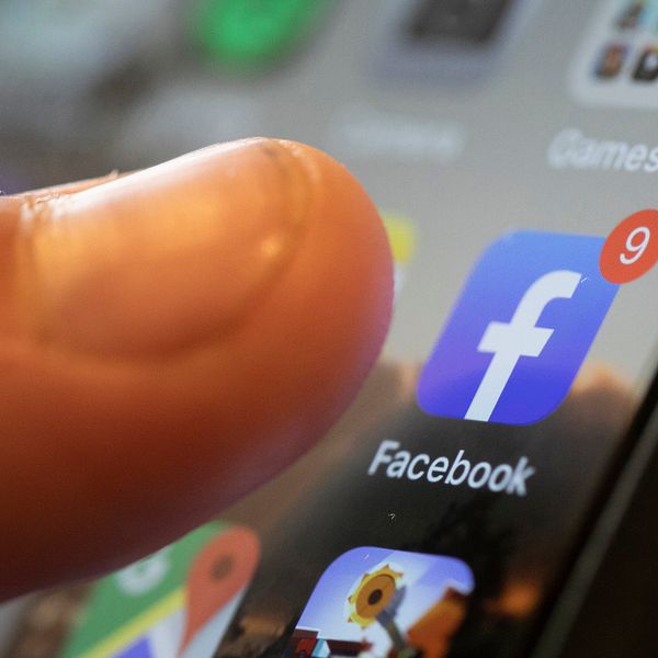 Tumme som trycker på Facebook-applikationen på en smartphone.