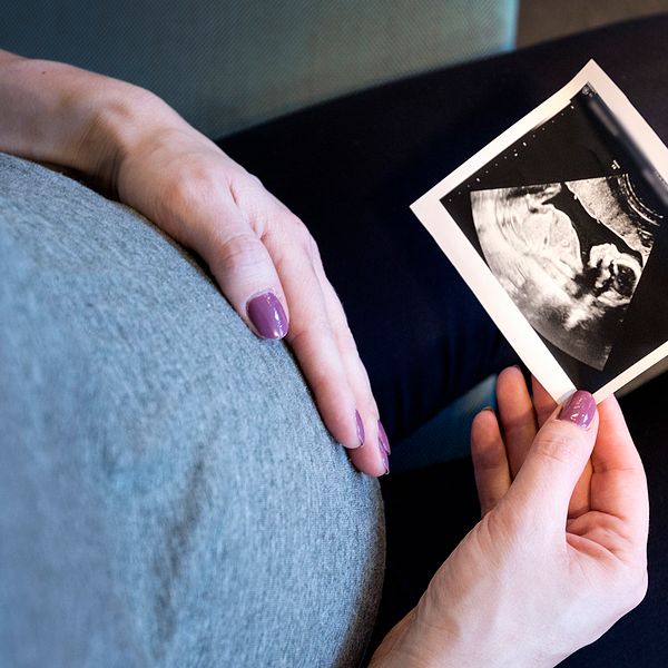 Genrebild. En gravid kvinna håller i ett ultraljudsfoto.